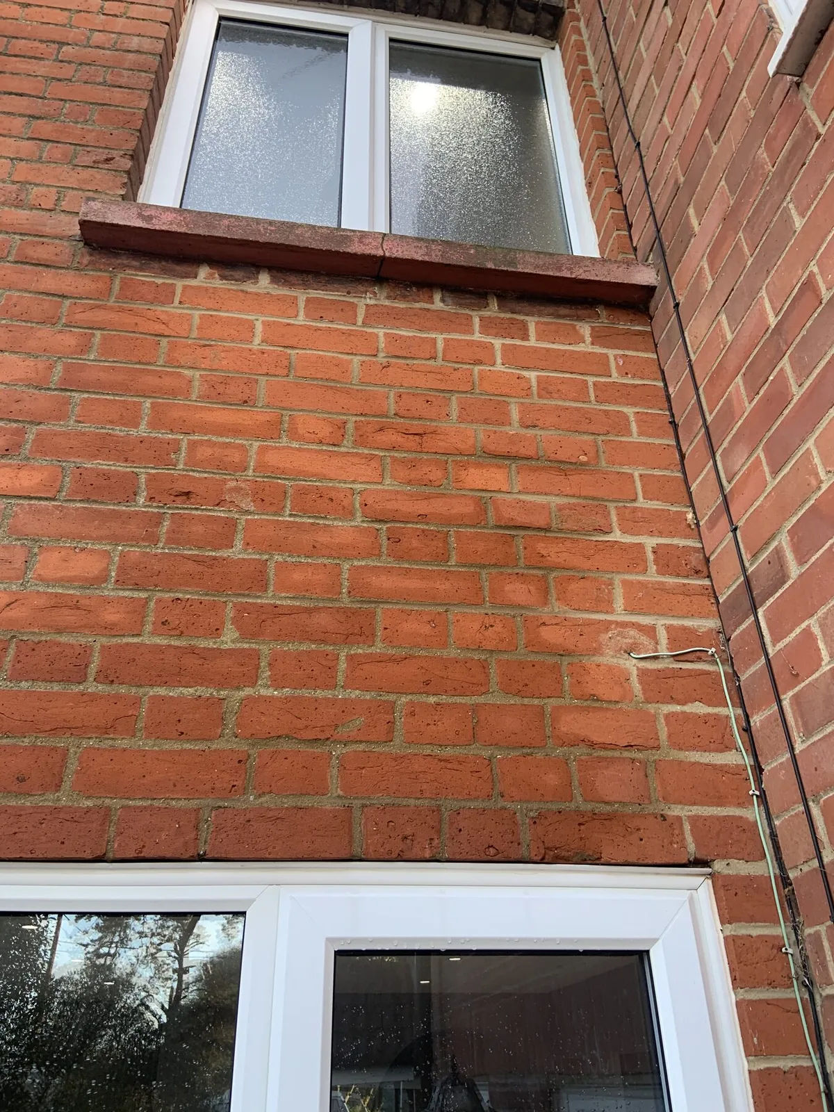 Porous red brickwork showing moisture saturation between windows