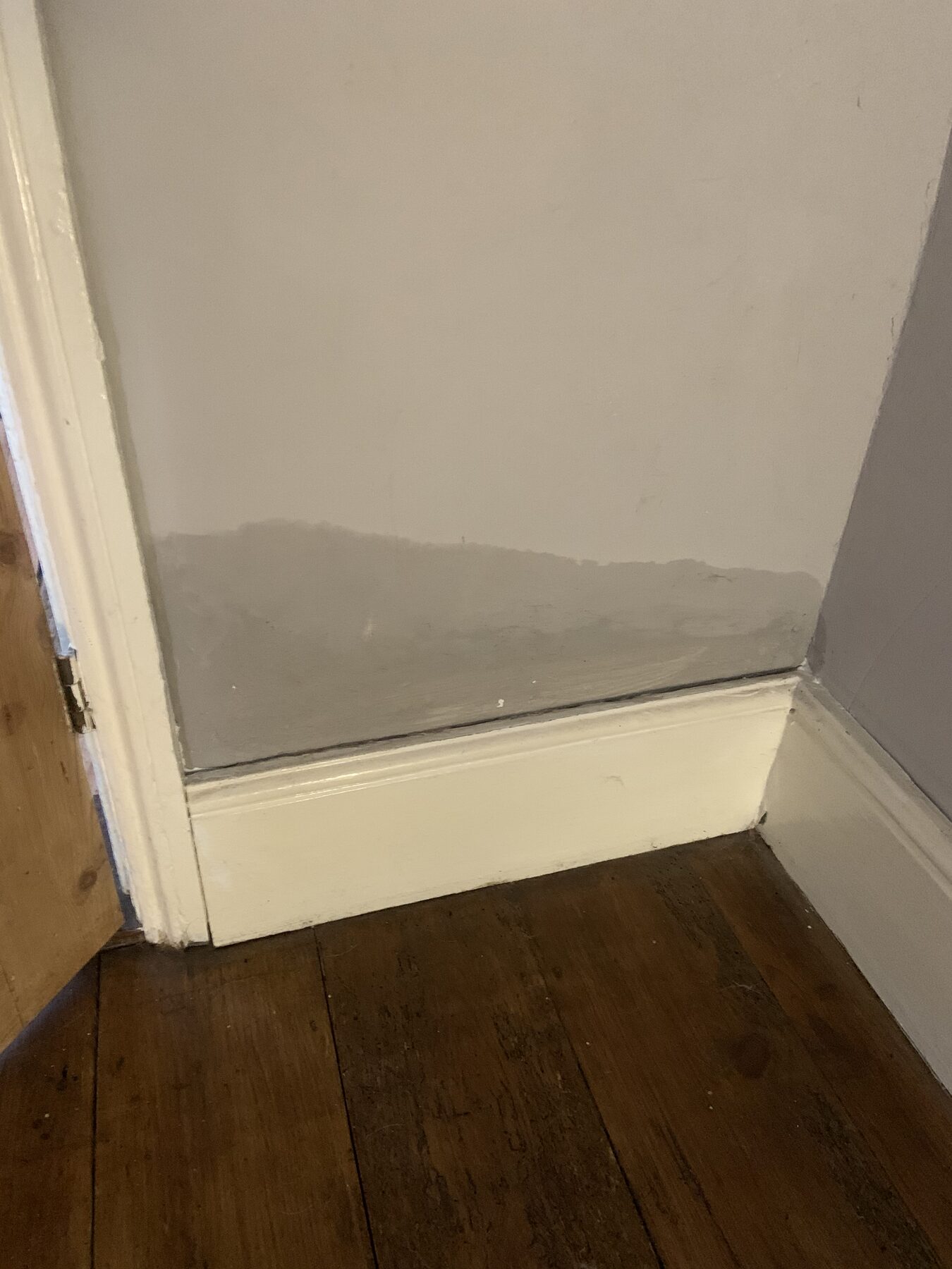 Subtle damp tide mark at low level on a wall beside a doorframe