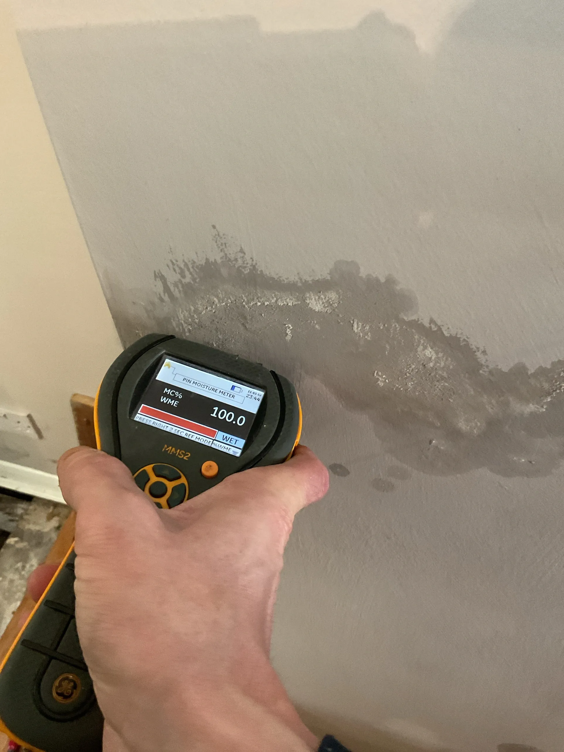 Professional moisture testing on a damp wall using an electronic moisture meter