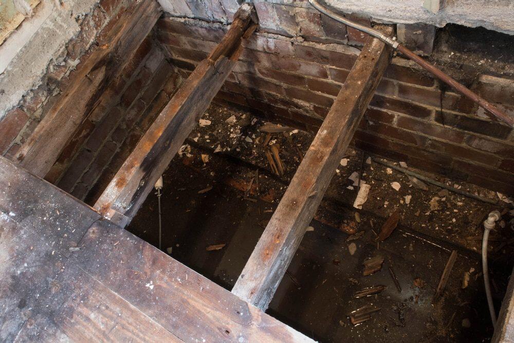 Rotten floor joists exposed showing severe wet rot decay